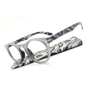 Augenstolz Fertiglesebrille Blixt Silver – runde Lesebrille mit transparent-grauem Rahmen, schräg auf dem Etui mit schwarz-weißem Wellenmuster liegend