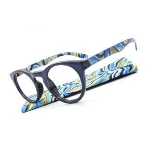 Augenstolz Fertiglesebrille Blixt Blue – runde Lesebrille mit dunkelblauem Rahmen, schräg auf dem Etui mit blau-gelb-schwarzem Wellenmuster liegend