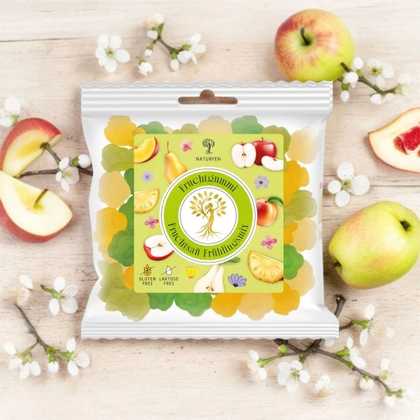 NATURFEH Fruchtgummi auf Joghurtschaum mit Blüten und Früchten im Hintergrund