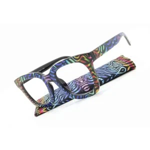 Augenstolz Fertiglesebrille Bonni Tasty – eckige Lesebrille mit buntem Wellenmuster auf schwarzem Grund, schräg auf dem passenden Etui liegend